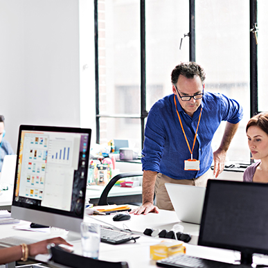 Office team discussing project with computer screens displaying data