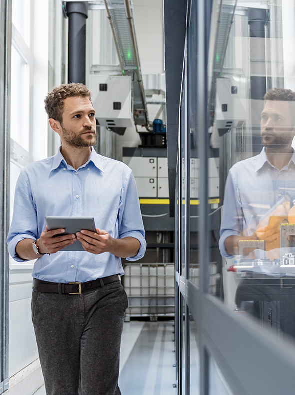 Engineer using a tablet in an industrial facility with machinery.